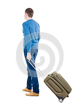 Back view of man with green suitcase looking up.