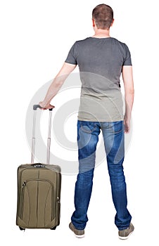 Back view of man with green suitcase looking up.