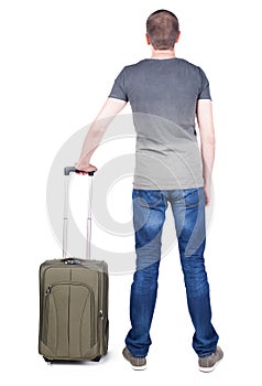 Back view of man with green suitcase looking up.