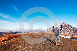 The back view of man, happy traveler and tramper in wild mountains of volcanic landscape, climber reached high spot, Tongariro