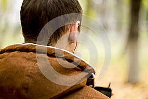 Back view of man with headphones holding mobile smart phone