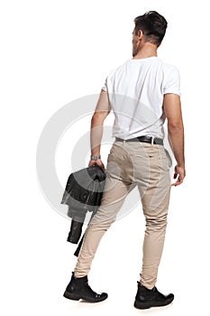 Back view of man holding jacket and walks