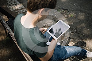 Back view of man holding tablet in park