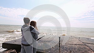 The back view of the man hugging the woman and enjoying the sea.