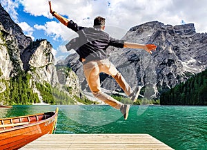 Back view of a man jumping on wooden pier in the Fanes-Sennes-Prags Nature Park in Italy