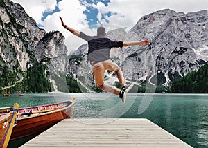 Back view of a man jumping on wooden pier in the Fanes-Sennes-Prags Nature Park in Italy