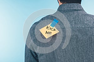 back view of man with note on sticky tape with kick me lettering on back, april fools day