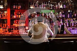 Back view of a man ordering drink to a bartender