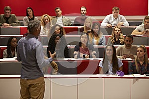 Back view of man presenting to students at a lecture theatre