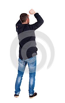 Back view of man. Raised his fist up in victory sign.