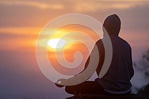 Back view of man is relaxingly practicing meditation yoga mudra at mountain top with sunrise in winter to attain happiness from