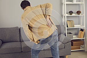 Back view of man with rheumatism feeling intense pain and touching his lower back