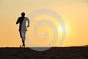 Back view of a man running on the beach at sunset