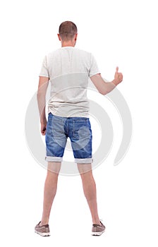 Back view of man in shorts shows thumbs up.