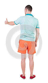 Back view of man in shorts shows thumbs up.