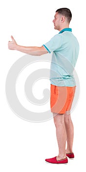 Back view of man in shorts shows thumbs up.