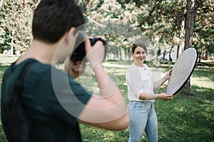 Back view of man taking photo session girl who is holding reflector