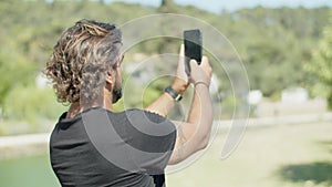 Back view of man taking photo of view during cycling in park