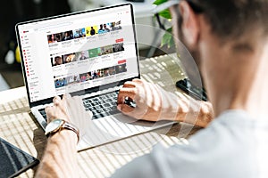 back view of man using laptop with youtube website