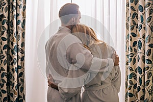 back view of mature couple in love wearing bathrobes and hugging in hotel