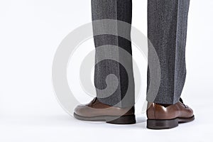 Back View of Mens Legs Wearing Brown penny Loafers. Against White Background