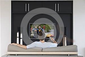 Back view of mid-adult man changing channels with television remote control in living room