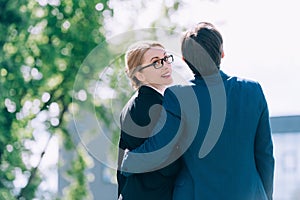 back view of middle aged business people embracing while standing together on street