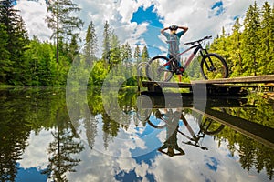 Back view of a modern e-mtb electric cyclist stretching or refreshing on a beautiful lake of Podolerteich, hidden gem in the