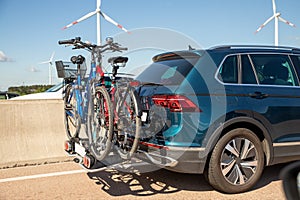 Back view modern white family wagon car with mounted roof box trunk and bike tail carrier driving european highway road