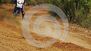 Back view of motocross rider driving fast on dirt track.