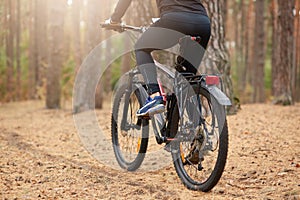 Back view of mountain biker riding on bike in autumn inspirational forest landscape, guy cycling MTB on enduro trail track, male