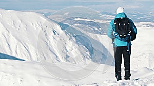 Back view of a Mountaineer wearing backpack. Snow-covered landscape - Cloudy Blue Sky