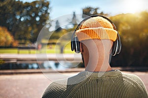 Back view, music headphones and man outdoor, listen to audio or streaming sound online. Radio, podcast and person at