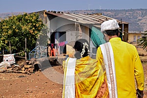 Back view newly married Indian couple walking together toward their home