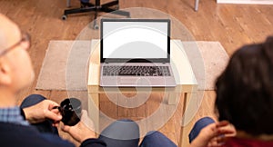 Back view of old couple in their living room looking a laptop with white isolated mock-up