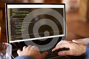 Back view over the shoulder shot of developer programmer with laptop. Program code and script data on the screen. Young