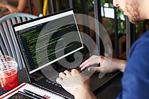 Developer programmer with laptop. Program code and script data on screen. Young freelancer in glasses working on project