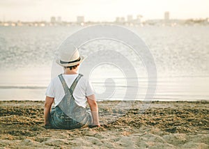 Back view of a Pensive child sitting on the beach