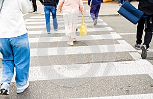 Back view, people on green traffic light cross road at pedestrian crossing