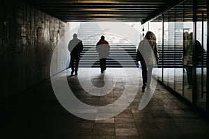 Back view of people walking in dark underground passway