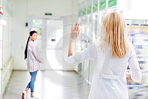 back view of pharmacist waving hand to pregnant woman