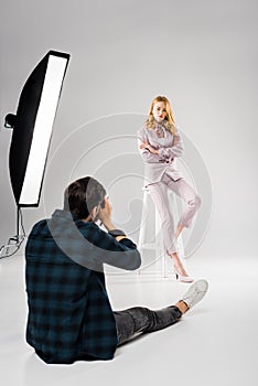back view of photographer sitting and photographing beautiful female model posing