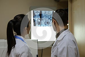 Back view: picture of two doctors exploring spinal x-ray