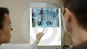 Back view: picture of two doctors exploring spinal x-ray: lumbar and cervical region - first