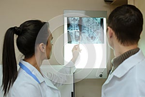 Back view: picture of two doctors exploring spinal x-ray: lumbar and cervical region - first 2 cervical vertebrae photo