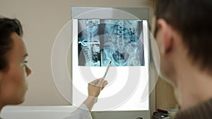 Back view: picture of two doctors exploring spinal x-ray: lumbar and cervical region - first photo