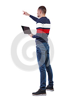 Back view of a pointing man who is standing with a laptop