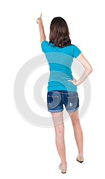 Back view of pointing woman. beautiful brunette girl in shorts