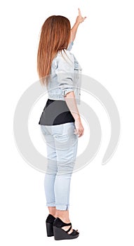 Back view of pointing woman. beautiful redhead girl in jeans.
