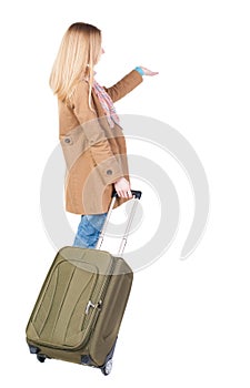 Back view of pointing woman with suitcase looking up.